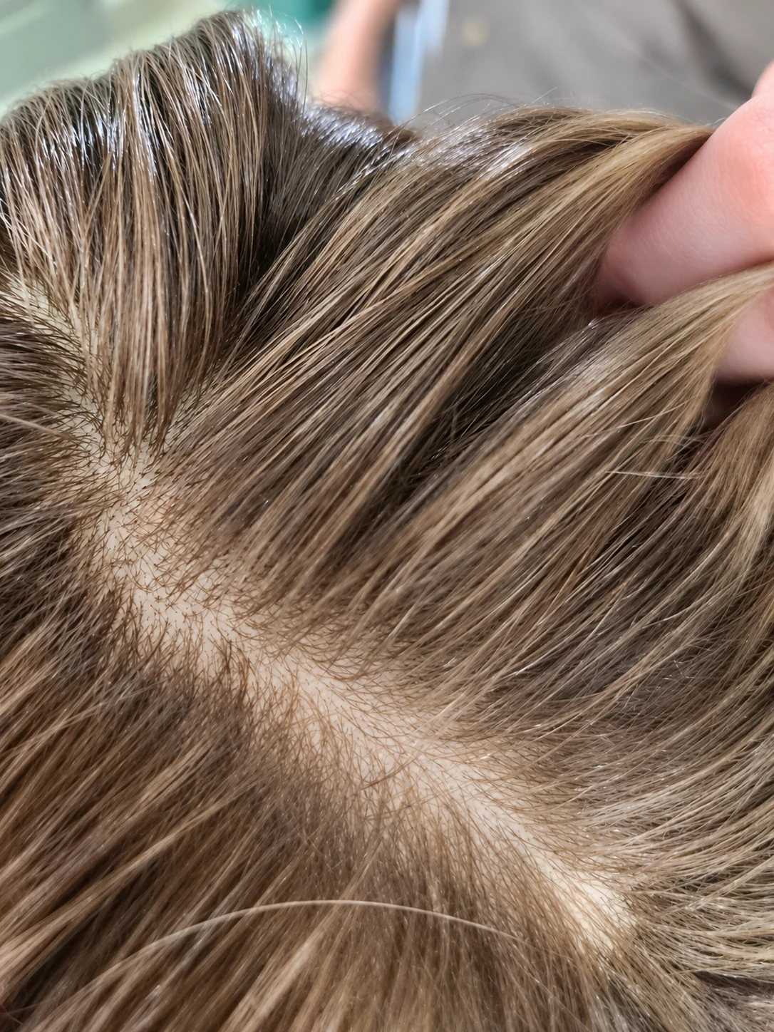 Close-up of blonde hair lifted beside a parting to show the discreet finish